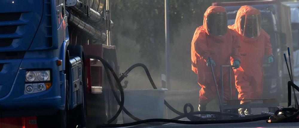 Feuerwehrleute in Schutzanzügen arbeiten auf der Zufahrt zur Raststätte Walsleben (Brandenburg) an einem leckgeschlagenen Lkw, der mit Salpetersäure beladen ist.