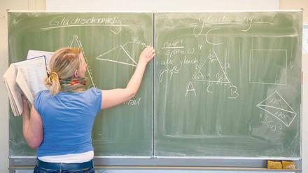 Eine Lehrerin erörtert ein mathematisches Problem an der Tafel.