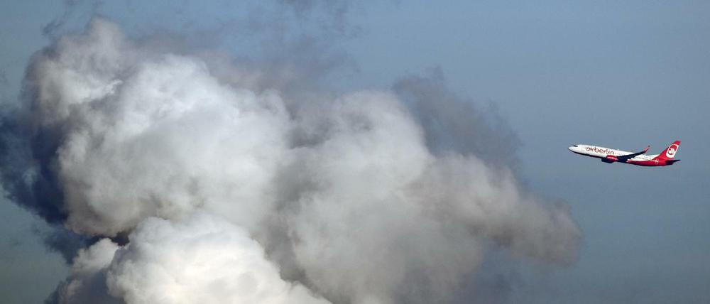 Ein Flugzeug der Airline "Air Berlin" fliegt an einer riesigen Wasserdampfwolke des Heizkraftwerkes Reuter in Siemensstadt vorbei.