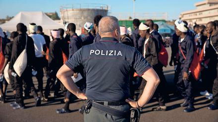 Ein Grenzbeamter beobachtet die Ankunft afrikanischer Flüchtlinge, die mit einem Rettungsboot Italien erreichten.