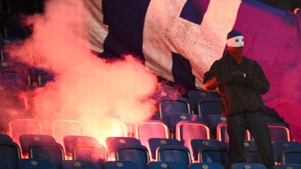 Rostocker Hooligans zünden Stadionsitze und einen Banner der Berliner an.