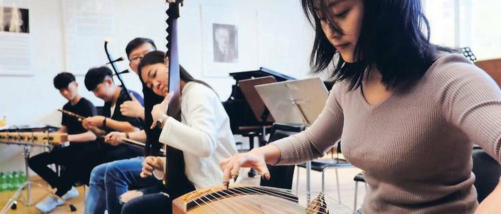 Traditionelle chinesische Instrumente. Jiakang Zhang (r.) spielt eine Guzheng, zu Deutsch: Wölbbrettzither. 