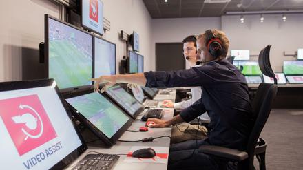 Der Schiedsrichter Sascha Stegemann sitzt in einem Videoassistcenter vor Monitoren, die Spielszenen zeigen. 