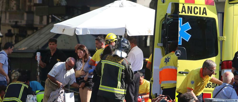 Sanitäter versorgen verletzte Menschen. Auf der Flaniermeile Las Ramblas ist ein Lieferwagen in eine Menschenmenge gerast. Es hat Tote und Verletzte gegeben.