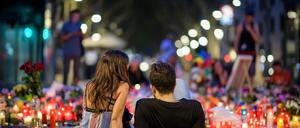 Ein Pärchen sitzt am 19.08.2017 in den frühen Morgenstunden vor niedergelegten Rosen und Kerzen auf der Flaniermeile Las Ramblas in Barcelona.