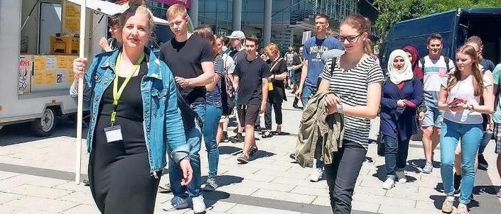 Eine Unimitarbeiterin führt eine Gruppe von Studieninteressierten über den Campus.