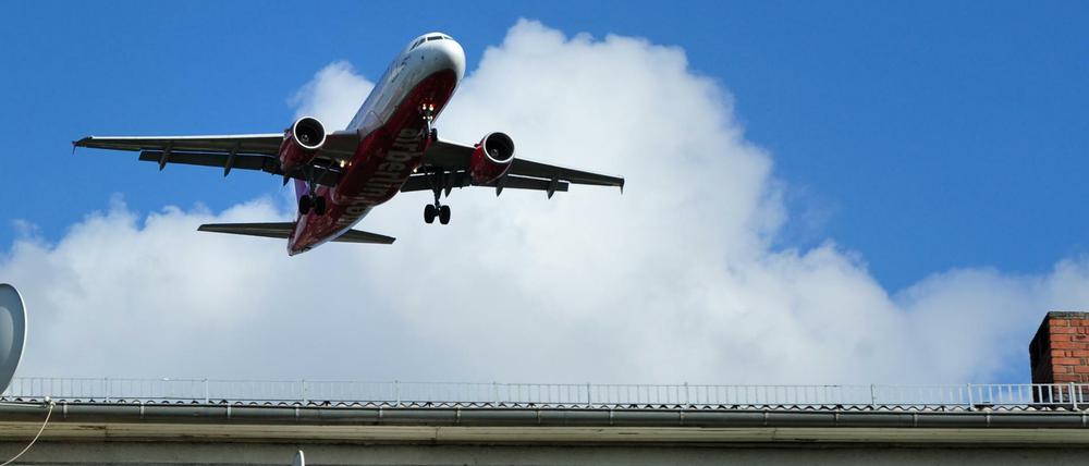 Ein lautes Flugzeug fliegt über ein Wohnhaus. 