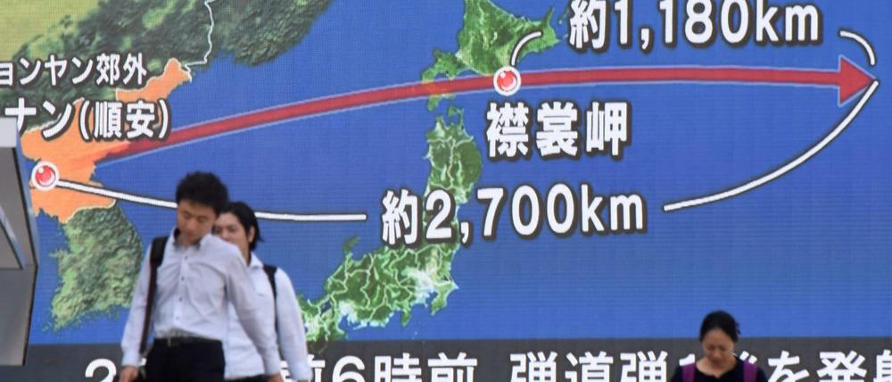 Passanten gehen in Tokio an einem TV-Screen vorbei, der die Laufbahn einer nordkoreanischen Rakete zeigt.