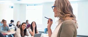 Eine Professorin spricht im Seminarraum mit Studierenden.