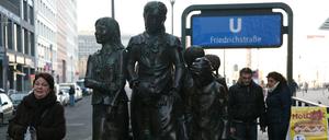 Passanten betrachten die Figurengruppe " Züge in das Leben- Züge in den Tod " vom Frank Meisler am Bahnhof Friedrichstraße in Berlin-Mitte.