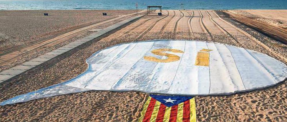 Zeichen setzen. Ein Ja zur Unabhängigkeit und eine katalanische Flagge auf einem Strand nahe Barcelona.