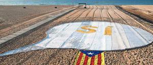Zeichen setzen. Ein Ja zur Unabhängigkeit und eine katalanische Flagge auf einem Strand nahe Barcelona. 