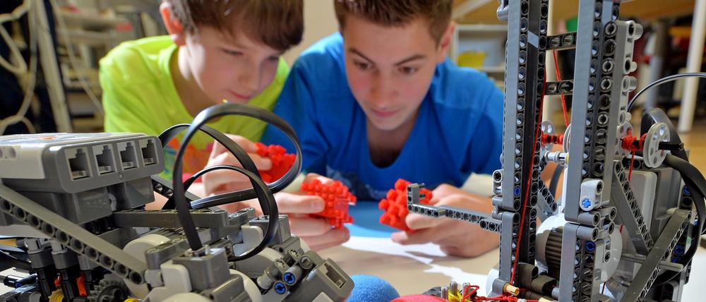 Zwei Schüler bauen an Roboter-Modellen.