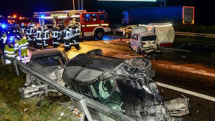 Feuerwehrleute stehen am 12.09.2017 auf der Autobahn 2 bei Oelde (Nordrhein-Westfalen) neben zerstörten PKW. 