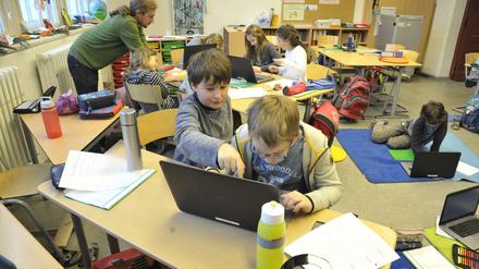 Grundschüler arbeiten im Klassenraum an Laptops.