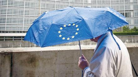 Ein Fußgänger vor dem EU-Kommissionsgebäude im Brüsseler Regen. 