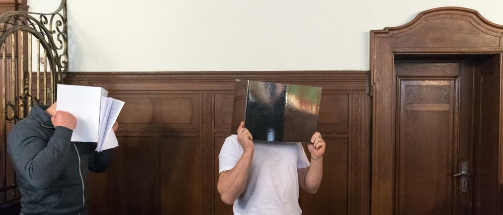 Die Angeklagten stehen am 13.09.2017 zu Prozessbeginn im Saal 621 des Landgerichts Berlin und verdecken ihr Gesicht. Die Männer sind wegen des brutalen Mordes an dem Musiker Jim Reeves in einem Berliner Hostel angeklagt. Der Sänger der Band Sqeezer war am 01. Februar 2016 getötet worden. 