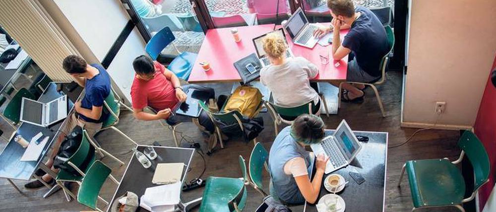 In einem Café arbeiten Menschen an ihren Laptops.