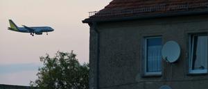 Ein Passagierflugzeug befindet sich im Landeanflug über den Dächern von Häusern im Ort Sielow unweit dem Flughafen Schönefeld. 