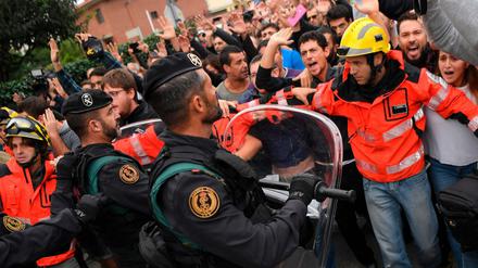 Feuerwehrleute halten eine Gruppe von Leuten vor Sicherheitskräften vor einer Wahlstation zurück. 