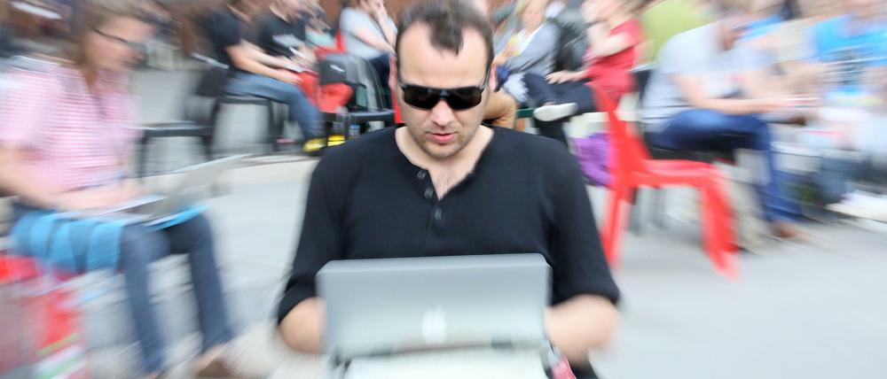 Ein Besucher der Internetkonferenz Re:publica mit seinem Laptop auf den Knien.