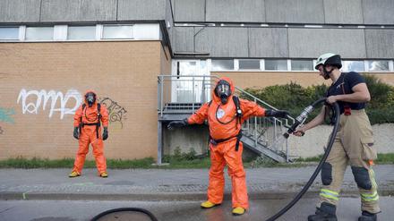 Einsatzkräfte der Feuerwehr werden nach ihrem Einsatz im Rahmen des Chlorgas-Austritts in einer Schwimmhalle in Berlin-Buch mit Wasser abgespritzt. 