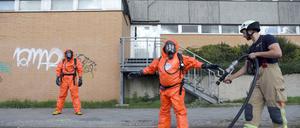 Einsatzkräfte der Feuerwehr werden nach ihrem Einsatz im Rahmen des Chlorgas-Austritts in einer Schwimmhalle in Berlin-Buch mit Wasser abgespritzt. 