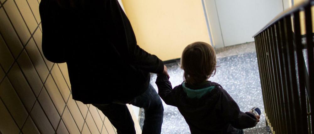 Eine alleinerziehende Mutter geht mit ihrem Sohn durch einen Hausflur die Treppe herunter. Es sind vor allem Frauen, die armutsgefährdet sind.