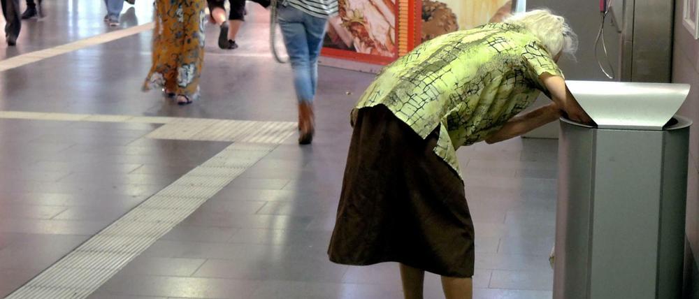 Eine alte Frau sammelt Flaschen aus Abfalleimern im Hauptbahnhof in Muelheim an der Ruhr. 