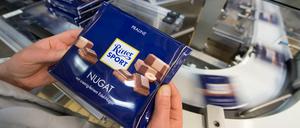 Eine Mitarbeiterin des Schokoladenherstellers Ritter Sport prüft die Verpackung einer Tafel Schokolade.