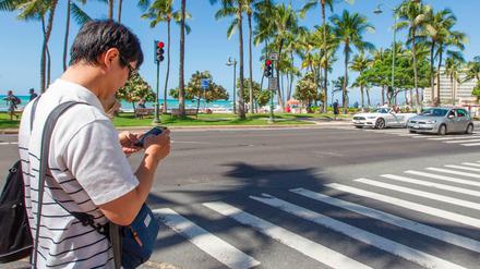 Das könnte teuer werden: Ein Fußgänger mit einem Mobiltelefon auf einem Zebrastreifen in Honolulu. 