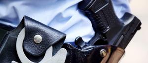 Polizist mit Waffe und Handschellen (Symbolbild)