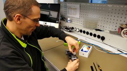 Mathias Gurisch vom Gravis-Technikcenter am Ernst-Reuter-Platz spannt ein iPhone X in ein spezielles Werkzeug zum Abheben des Displays. 