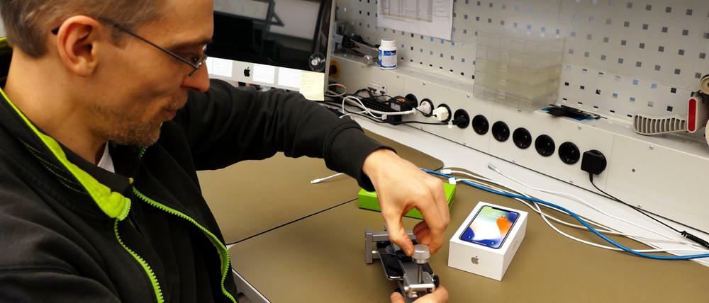 Mathias Gurisch vom Gravis-Technikcenter am Ernst-Reuter-Platz spannt ein iPhone X in ein spezielles Werkzeug zum Abheben des Displays. 