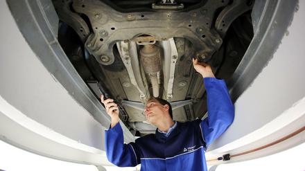 Ein TÜV-Prüfer kontrolliert bei einer Hauptuntersuchung einen PKW.