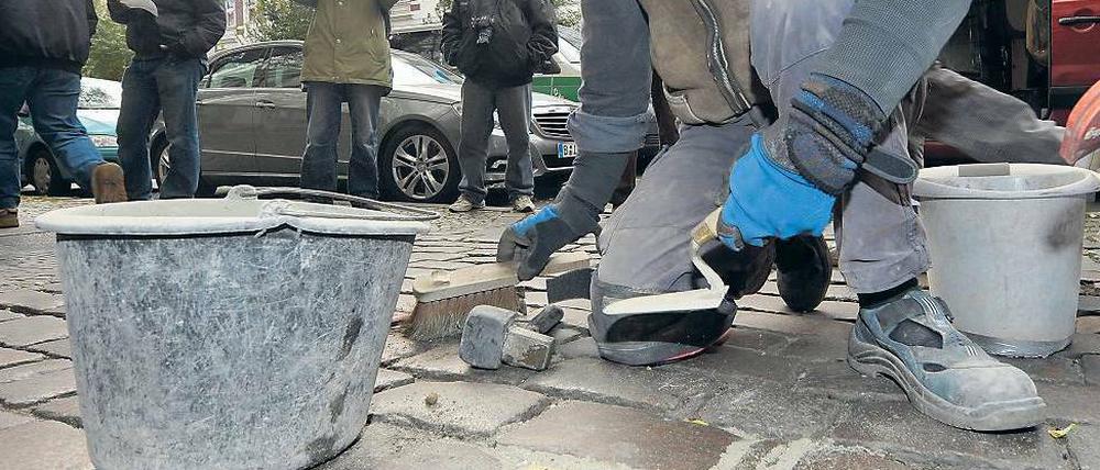 Künstler Gunter Demnig verlegt Gedenksteine auf einem Berliner Gehweg.