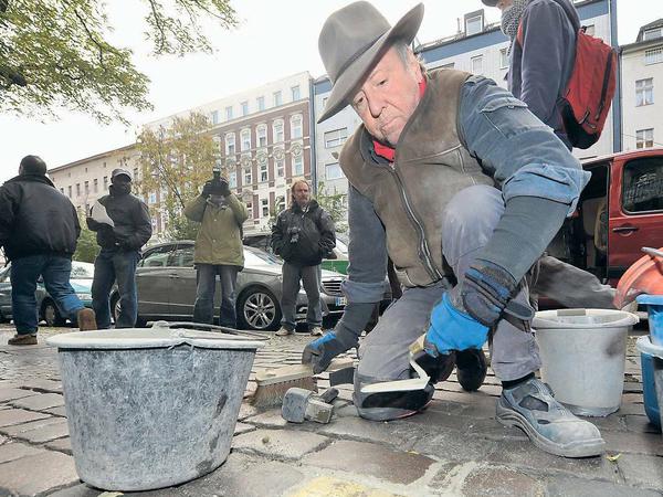 Künstler Gunter Demnig verlegt Gedenksteine auf einem Berliner Gehweg.