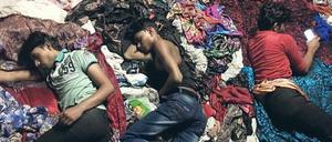 Erschöpft. Indische Arbeiter schlafen im Stofflager.