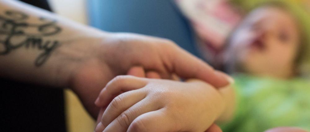 Nicht nur Senioren. Eine Pflegefachkraft hält die Hand eines dreijährigen Mädchens einer Intensivpflege-Wohngruppe für kranke Kinder. -