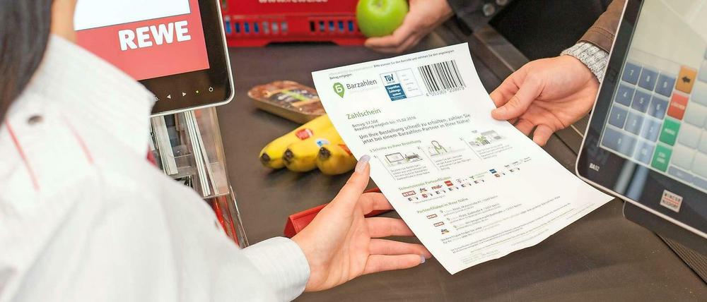 Die Kassiererin scannt den Zahlschein ein, dann bekommt der Arbeitslose sein Geld ausgezahlt.