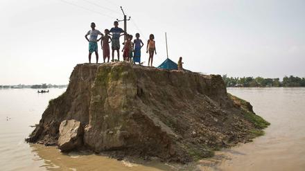 Dorfbewohner warteten im vergangenen August auf einer von den Überschwemmungen zerstörten Straße in Guwahati (Indien) auf Hilfsgüter. 