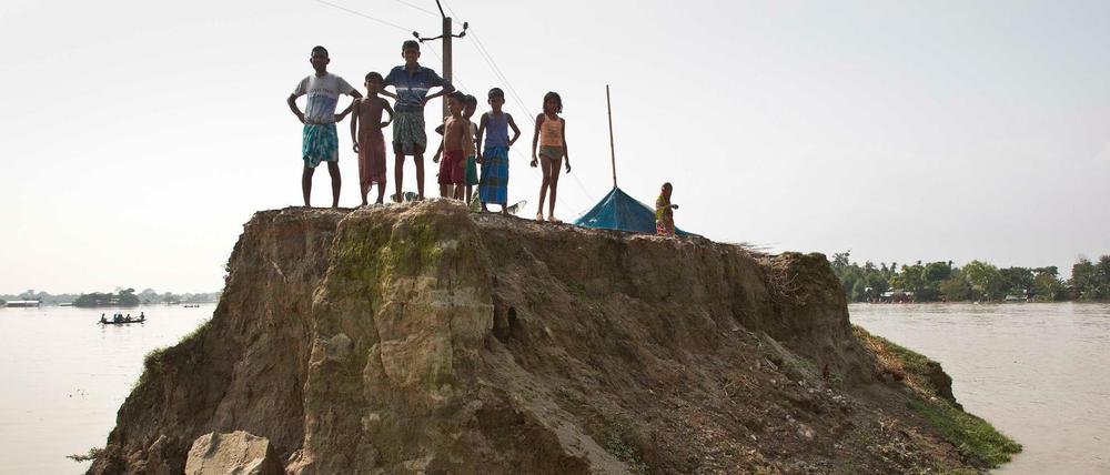 Dorfbewohner warteten im vergangenen August auf einer von den Überschwemmungen zerstörten Straße in Guwahati (Indien) auf Hilfsgüter. 