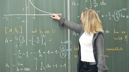 Eine junge Mathematikerin rechnet an der Tafel.