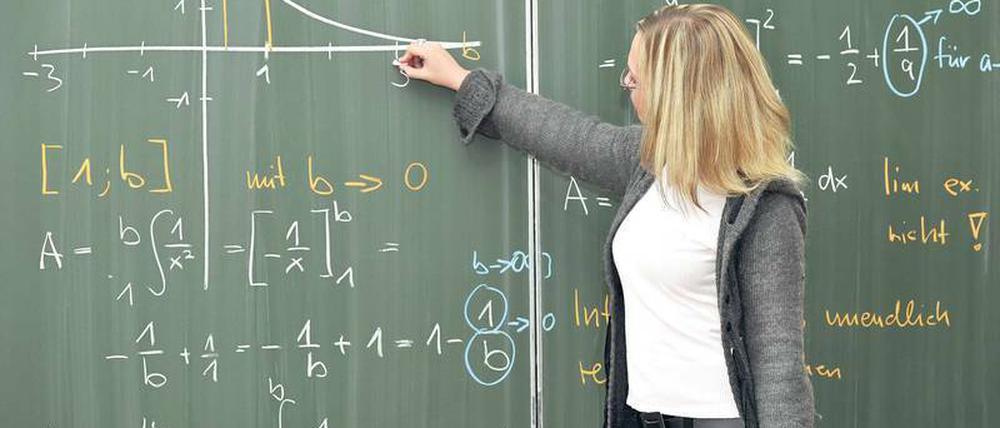 Eine junge Mathematikerin rechnet an der Tafel.