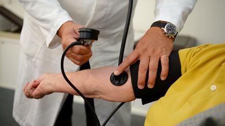 Ein Hausarzt misst einer Patientin den Blutdruck. 