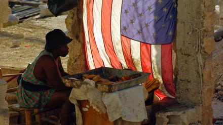 Eine Frau verkauft im Mai 2010 in Port-au-Prince, Haiti, gebackene Bananen und sitzt neben einer US-Nationalflagge.