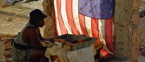Eine Frau verkauft im Mai 2010 in Port-au-Prince, Haiti, gebackene Bananen und sitzt neben einer US-Nationalflagge.