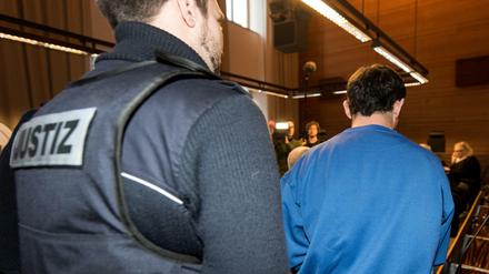 Der wegen Mordes und besonders schwerer Vergewaltigung angeklagter 40-jähriger Lastwagenfahrer wird von einem Justizmitarbeiter in den Sitzungssaal des Landgerichtes in Freiburg gebracht.