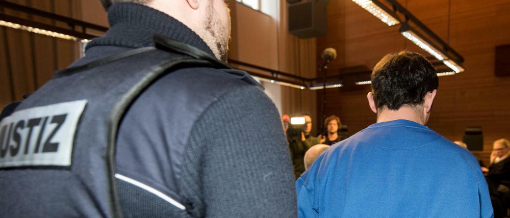 Der wegen Mordes und besonders schwerer Vergewaltigung angeklagter 40-jähriger Lastwagenfahrer wird von einem Justizmitarbeiter in den Sitzungssaal des Landgerichtes in Freiburg gebracht.