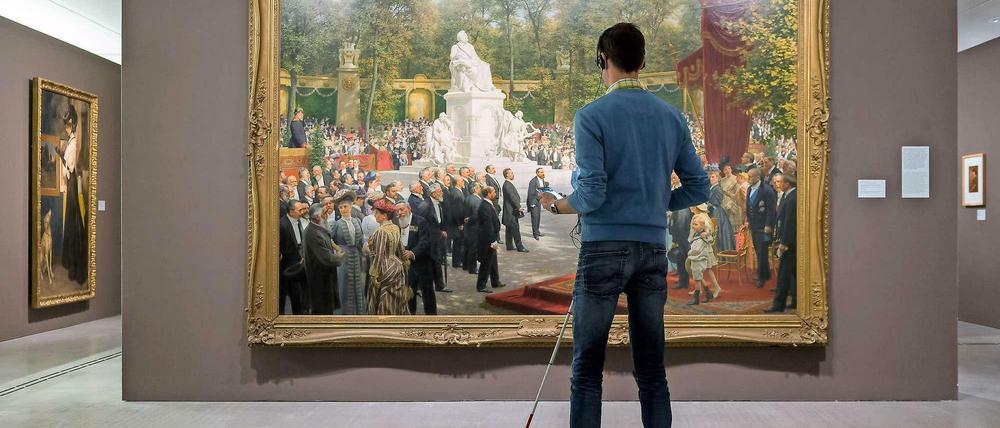 Kunst erleben mit taktilem Bodenleitsystem und Audio-App. Ein Besucher der Berlinischen Galerie vor dem Werk „Enthüllung des Richard-Wagner-Denkmals im Tiergarten“ von Anton von Werner, 1908.